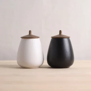 side view of pear shaped frosted ceramic tea jar with bronze metal lid