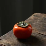 full view of orange persimmon shaped ceramic tea jar