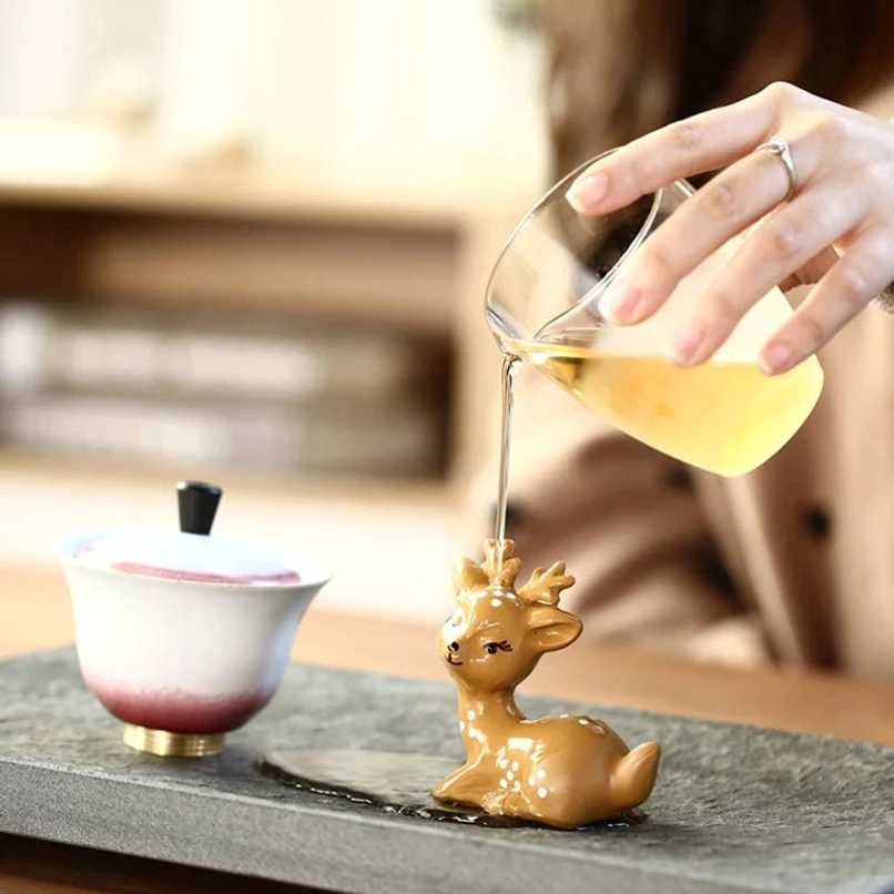 Hot tea being poured over sika deer purple clay tea pet during traditional Chinese tea ceremony