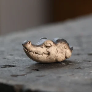 handcrafted purple clay closed-eye crocodile tea pet on tea tray