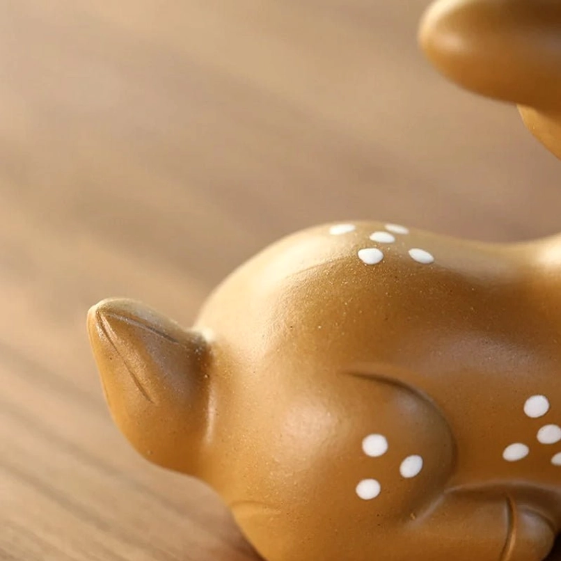 Winking sika deer tea pet placed on wooden desktop as cute kawaii home decor accent