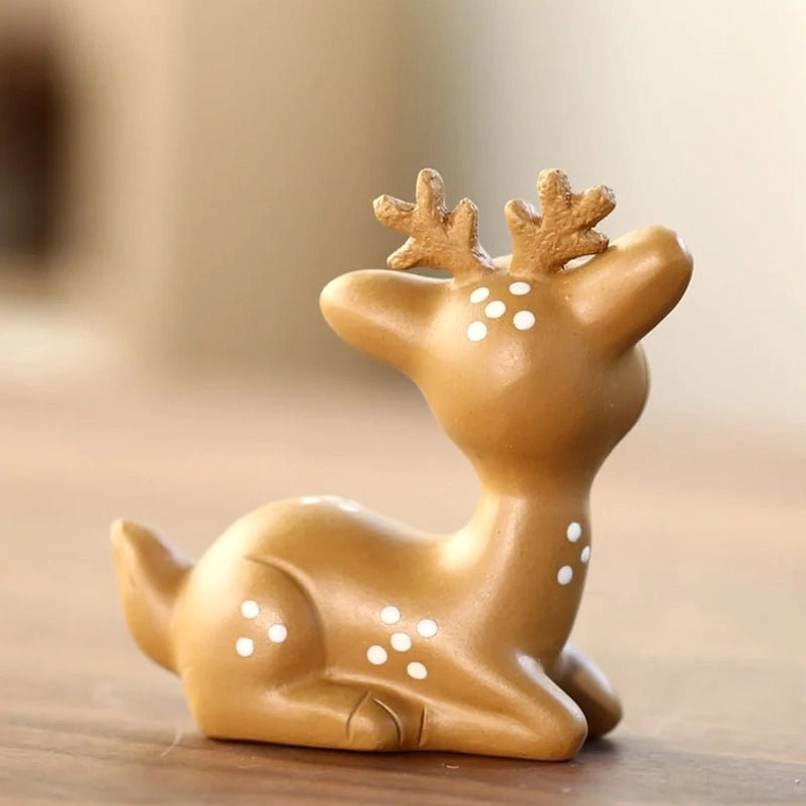 Hand holding small sika deer tea pet to show compact portable size