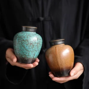 Hand holding small glazed ceramic tea jar