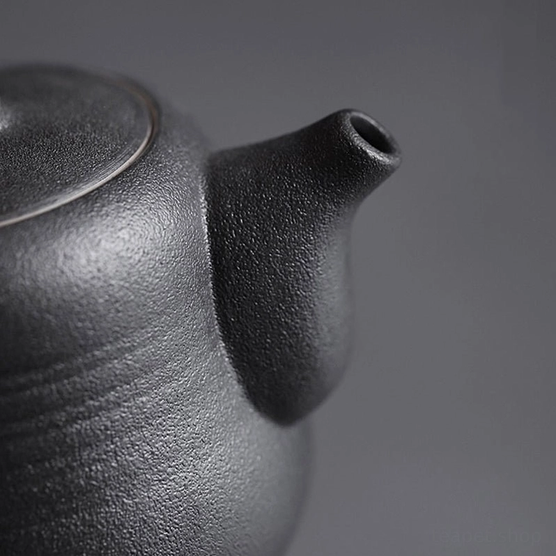Side view of three-footed base on wrapped handle ceramic teapot