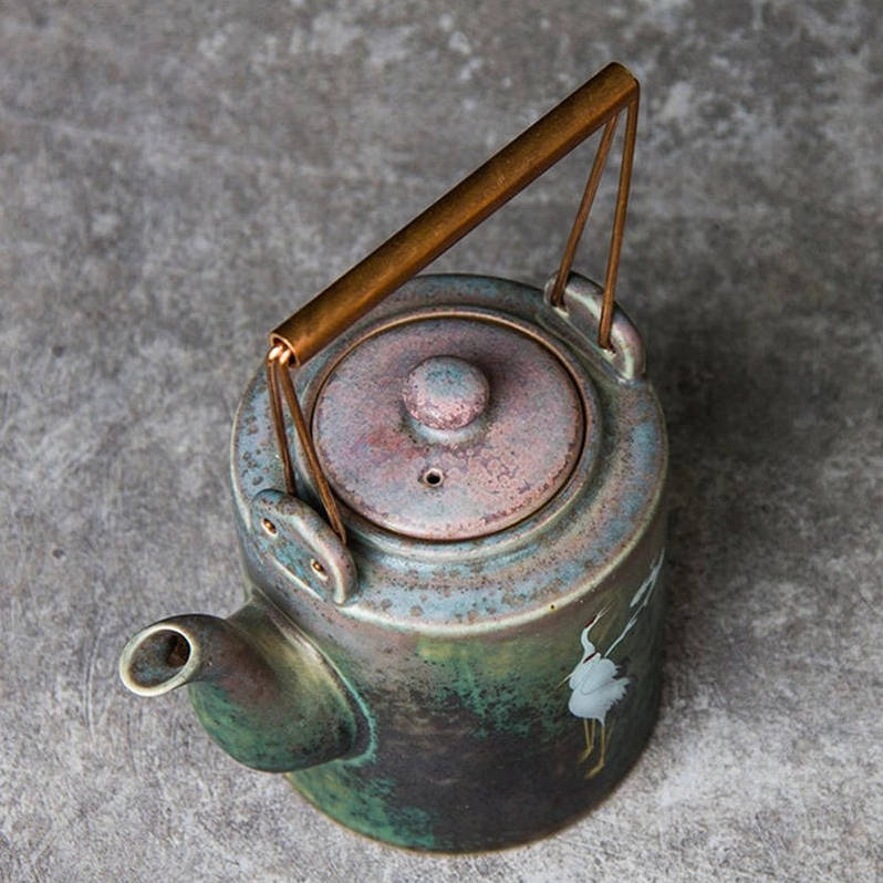 side view of traditional chinese crane motif ceramic teapot with copper handle