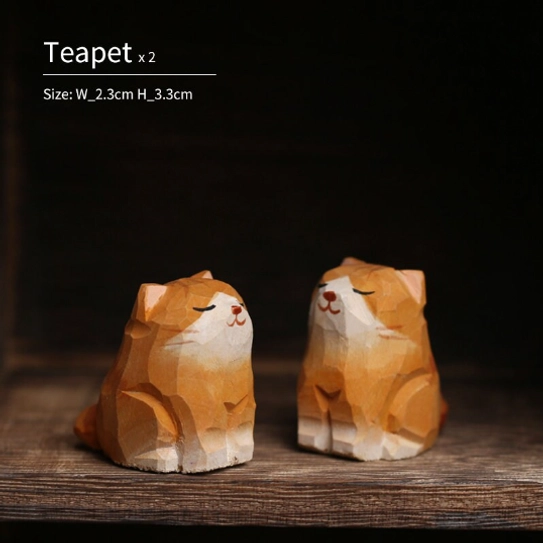 Two hand-carved cat tea pets placed on a wooden tea table for gongfu tea ceremony