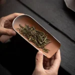 vintage ceramic tea scoop with metal trim displayed on wood background