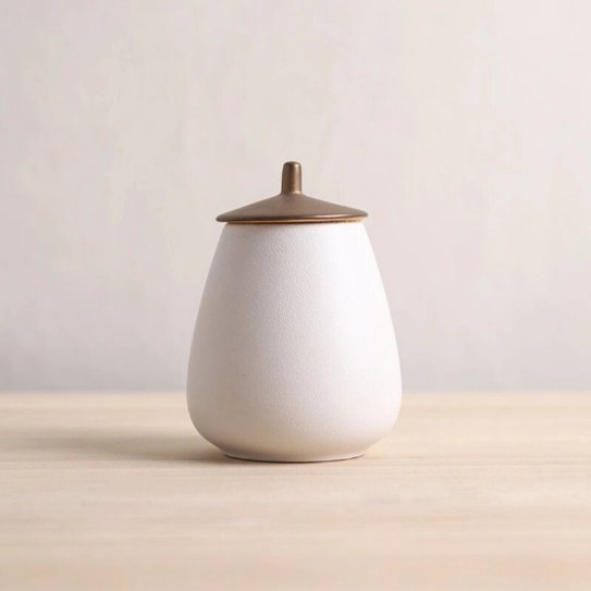 white pear shaped frosted ceramic tea jar with bronze metal lid