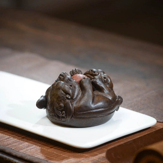 close up of detailed carving on double pixiu tea pet face and lucky ball