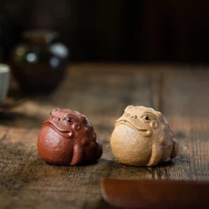 Handcrafted red Yixing Zisha lucky money toad tea pet on a wooden tea tray