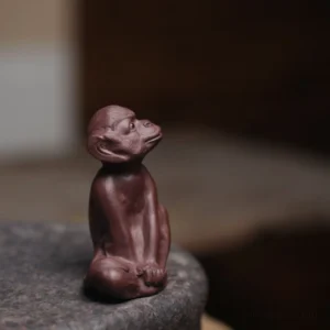 Handcrafted brown Yixing zisha monkey tea pet front view on stone tea tray